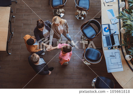 Top view of colleagues putting their arms in centre standing at modern office. Community concept Top view of colleagues putting their arms in centre standing at modern office. Community concept 105661818