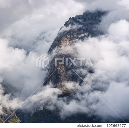 Mountain peak in low clouds at sunset. Dramatic landscape 105662677