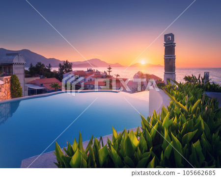 Beautiful swimming pool, green bush and orange roofs at sunset Beautiful swimming pool, green bush and orange roofs at sunset 105662685