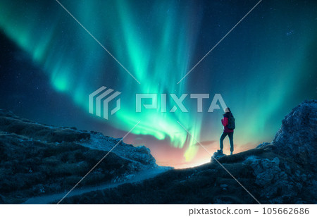 Northern lights and young woman on mountain peak at night. Auror 105662686