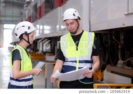 Young caucasian engineer man and woman or worker look blueprint and checking electric train. 105662919