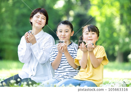 Adults and children eating rice balls outside Adults and children eating rice balls outside 105663316