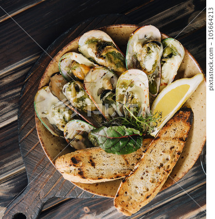 Cooked mussels in clay dish with bread and white wine glass 105664213