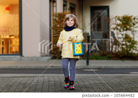 Little preschool kid girl holding selfmade traditional lanterns with candle for St. Martin procession. child happy about children and family parade in kindergarten. German tradition Martinsumzug Little preschool kid girl holding selfmade traditional lanterns with candle for St. Martin procession. child happy about children and family parade in kindergarten. German tradition Martinsumzug 105664482