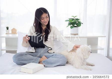 Beautiful young asian woman smile sitting using on digital tablet computer with dog. Beautiful young asian woman smile sitting using on digital tablet computer with dog. 105664572