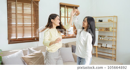 Loving LGBTQIA lesbian gay couple enjoy dancing together in the living room. Homosexual-LGBTQ concept. 105664892