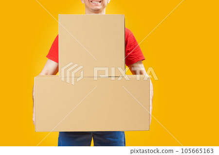 Man holding large cardboard boxes on bright yellow background. Courier or postman with parcels. Copy space, mock up. Space for text Man holding large cardboard boxes on bright yellow background. Courier or postman with parcels. Copy space, mock up. Space for text 105665163