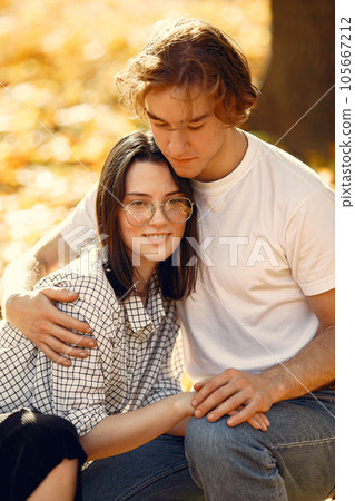 Couple in a park. Guy in a white t-shirt. Golden autumn. 105667212