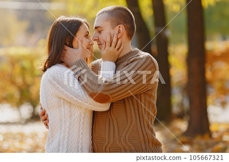 Couple in a park. Woman in a white sweater. Man in a brown sweater. Couple in a park. Woman in a white sweater. Man in a brown sweater. 105667321