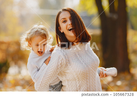 Fashionable mother with daughter. Family in a autumn park. Little girl in a white sweater. 105667328