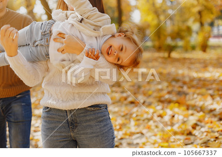 Family with cute little daughter. Father in a brown sweater. Family in a autumn field 105667337