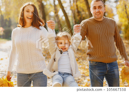 Family with cute little daughter. Father in a brown sweater. Family in a autumn field 105667338