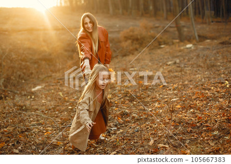 Fashionable mother with daughter. Family in a autumn park. Little daughter in a brown coat. Fashionable mother with daughter. Family in a autumn park. Little daughter in a brown coat. 105667383