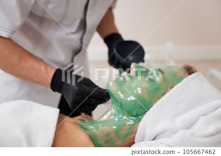 beautician applies alginate mask to the face of woman beautician applies alginate mask to the face of woman 105667462