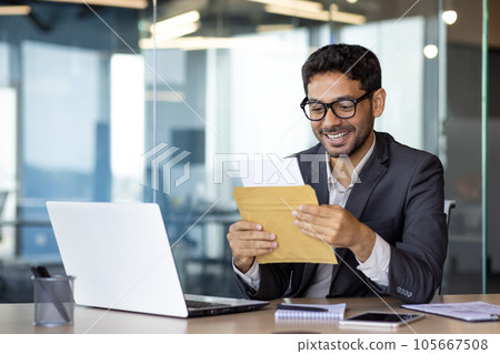 Young successful arab businessman at workplace inside office, man smiling satisfied received mail letter envelope notification message with good news, boss in business suit. 105667508