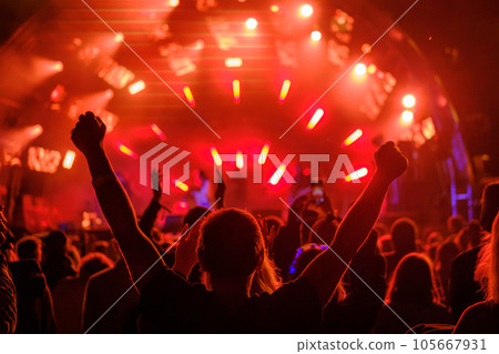 Fans with raised arms against glowing stage Fans with raised arms against glowing stage 105667931