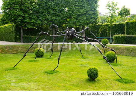 Sculpture of a huge black metal spider in the park. Contemporary unusual art Sculpture of a huge black metal spider in the park. Contemporary unusual art 105668019