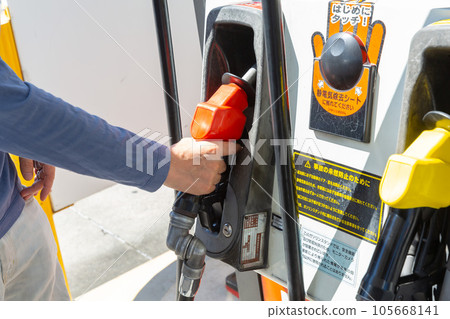 一個在加油站用自助服務為汽車加油的男人的手 一個在加油站用自助服務為汽車加油的男人的手 105668141