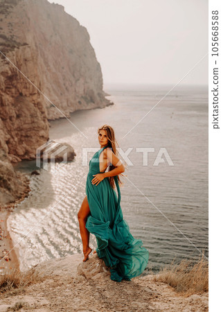 Woman sea trevel green dress. Side view a happy woman with long hair in a long mint dress posing on a beach with calm sea bokeh lights on sunny day. Girl on the nature on blue sky background. Woman sea trevel green dress. Side view a happy woman with long hair in a long mint dress posing on a beach with calm sea bokeh lights on sunny day. Girl on the nature on blue sky background. 105668588