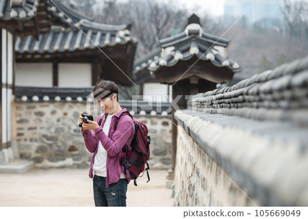 A young man holding a camera and taking pictures during a trip to Korea 105669049