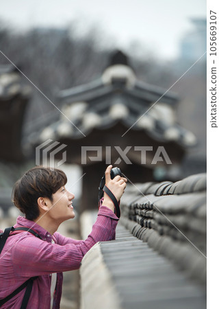 A young man holding a camera and taking pictures during a trip to Korea 105669107