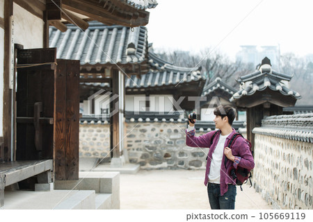A young man holding a camera and taking pictures during a trip to Korea 105669119