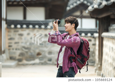 A young man holding a camera and taking pictures during a trip to Korea A young man holding a camera and taking pictures during a trip to Korea 105669124