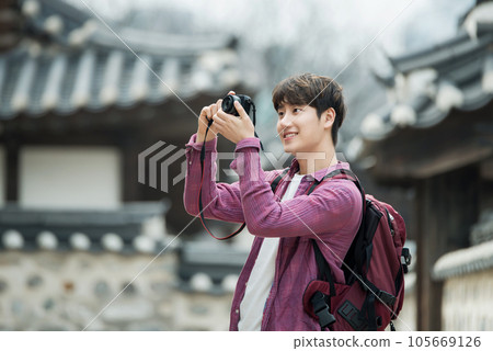 A young man holding a camera and taking pictures during a trip to Korea A young man holding a camera and taking pictures during a trip to Korea 105669126