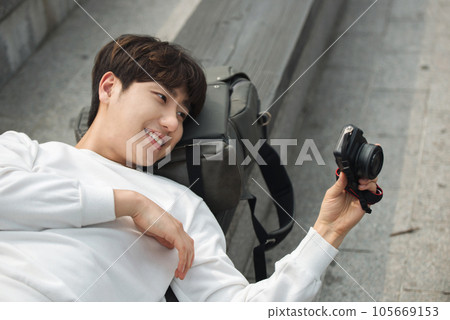 A young man holding a camera and taking pictures during a trip to Korea 105669153
