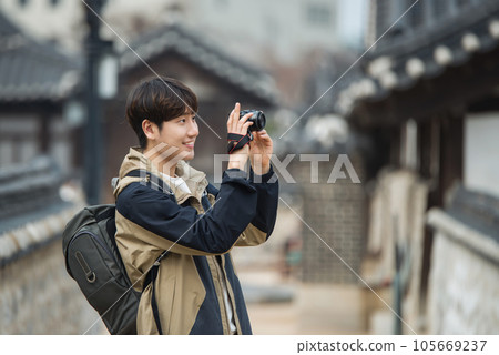 A young man holding a camera and taking pictures during a trip to Korea A young man holding a camera and taking pictures during a trip to Korea 105669237