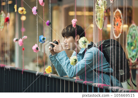 A young man holding a camera and taking pictures during a trip to Korea 105669515