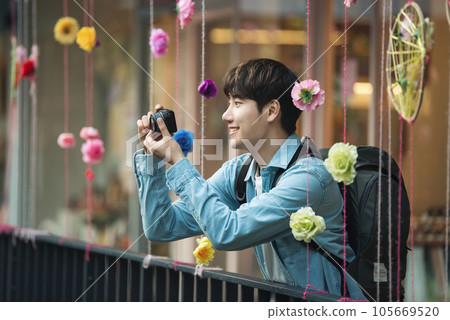 A young man holding a camera and taking pictures during a trip to Korea 105669520