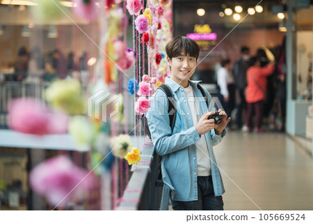 A young man holding a camera and taking pictures during a trip to Korea A young man holding a camera and taking pictures during a trip to Korea 105669524