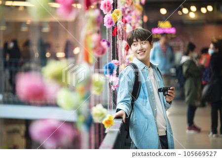 A young man holding a camera and taking pictures during a trip to Korea A young man holding a camera and taking pictures during a trip to Korea 105669527