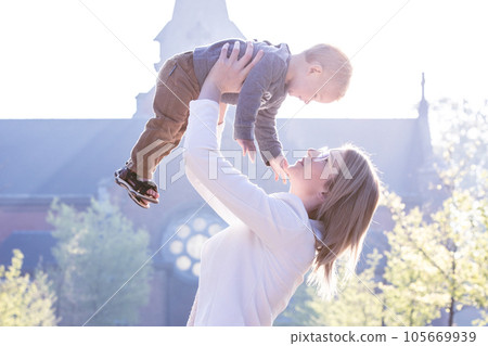 Joyful Bond: Blonde Millennial Mother Playfully Tossing her One-Year-Old Son in the Air at the Park Joyful Bond: Blonde Millennial Mother Playfully Tossing her One-Year-Old Son in the Air at the Park 105669939