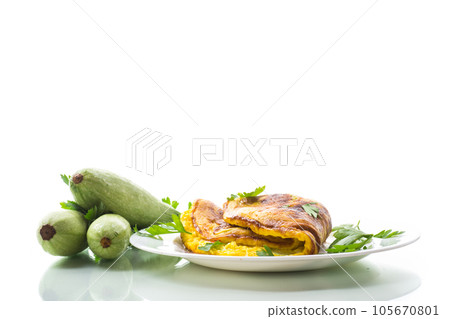 Fried omelette with zucchini,in a plate on a white background. Fried omelette with zucchini,in a plate on a white background. 105670801