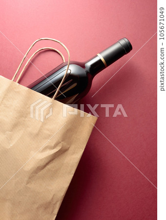 Paper shopping bag with a bottle of red wine. 105671049