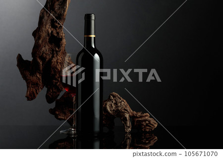 Red wine and old snag on a black background. 105671070