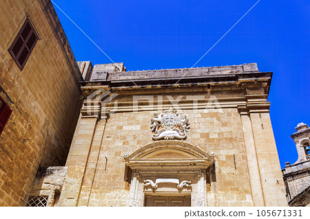 Birgu, Malta Oratory of The Holy Cross exterior with limestone and marble decoration detail at the old city of Citta Vittoriosa, under a bright blue sky. 105671331