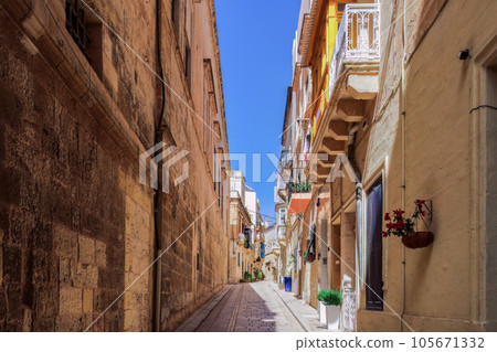 Traditional Maltese limestone buildings with coloured balconies in the vibrant alleys of the old city Birgu, Citta Vittoriosa without crowd. 105671332