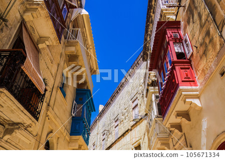Traditional Maltese limestone buildings with coloured balconies in the vibrant alleys of the old city Birgu, Citta Vittoriosa without crowd. 105671334
