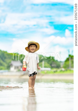 child standing on the beach in summer 105671389