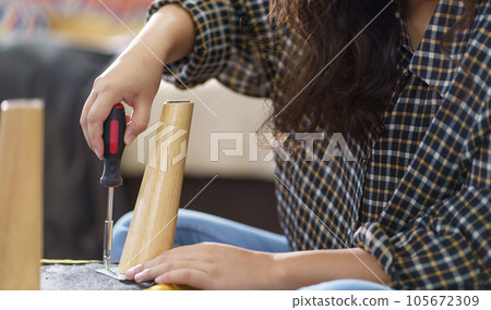 Asian Woman self repairs furniture renovation using equipment to diy repairing furniture sitting on the floor at home 105672309