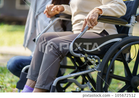 Family relationship Asian senior woman in wheelchair with happy daughter holding caregiver for a hand while spending time together Family relationship Asian senior woman in wheelchair with happy daughter holding caregiver for a hand while spending time together 105672512