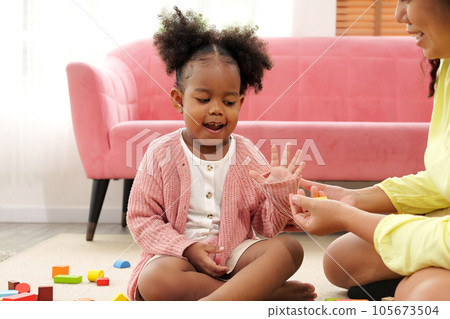 Happy mother spending time playing toys with daughter 105673504