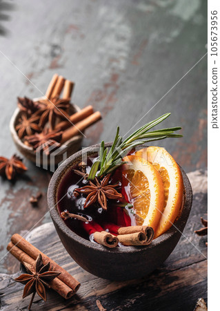 Mulled wine in ceramic mug with spices close up. Christmas hot drink on wooden table Mulled wine in ceramic mug with spices close up. Christmas hot drink on wooden table 105673956