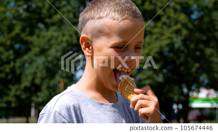 A boy eats an ice cream cone in the park A boy eats an ice cream cone in the park 105674446