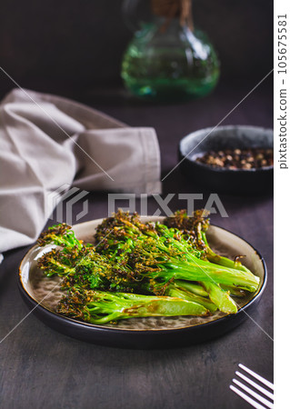 Fried green broccoli sprouts on a plate on the table vertical view 105675581
