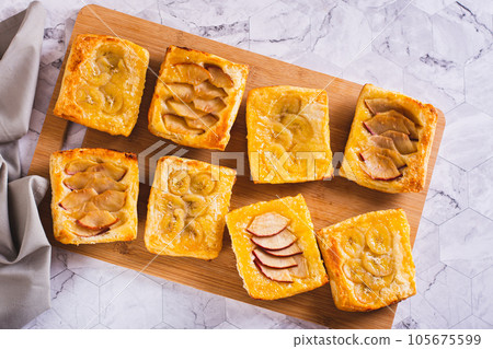 Small upside-down puff pastry tarts with apple and banana on the board top view 105675599