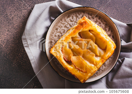 Close up of upside down puff pastry apple tart on a breakfast plate top view Close up of upside down puff pastry apple tart on a breakfast plate top view 105675608